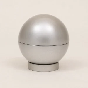 Unbranded ball shaped tin container on a warm gray studio background