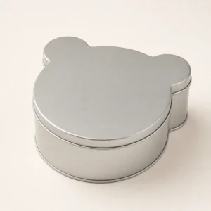 Unbranded bear shape tin box on a warm gray studio background