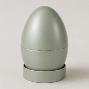Unbranded egg shaped seasonal tin on a warm gray studio background