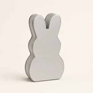 Unbranded rabbit shape tin box on a warm gray studio background