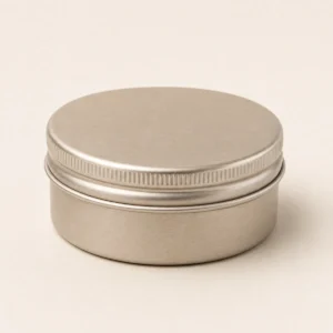 Unbranded round cosmetic tin on a warm gray studio background